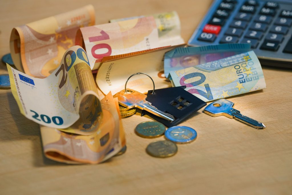 Maquette de maison, pièces de monnaie et calculatrice symbolisant le calcul des droits de succession