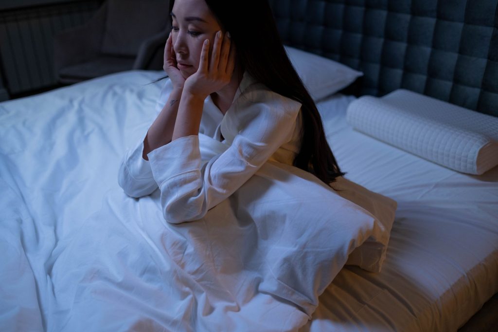 Femme éveillée la nuit, signe d'insomnie liée au stress chronique