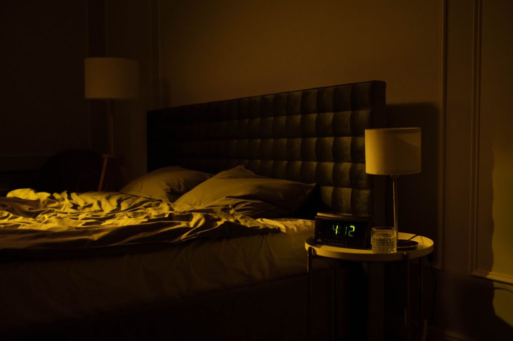Réveil dans une chambre sombre la nuit, illustrant les réveils précoces liés à l’anxiété nocturne