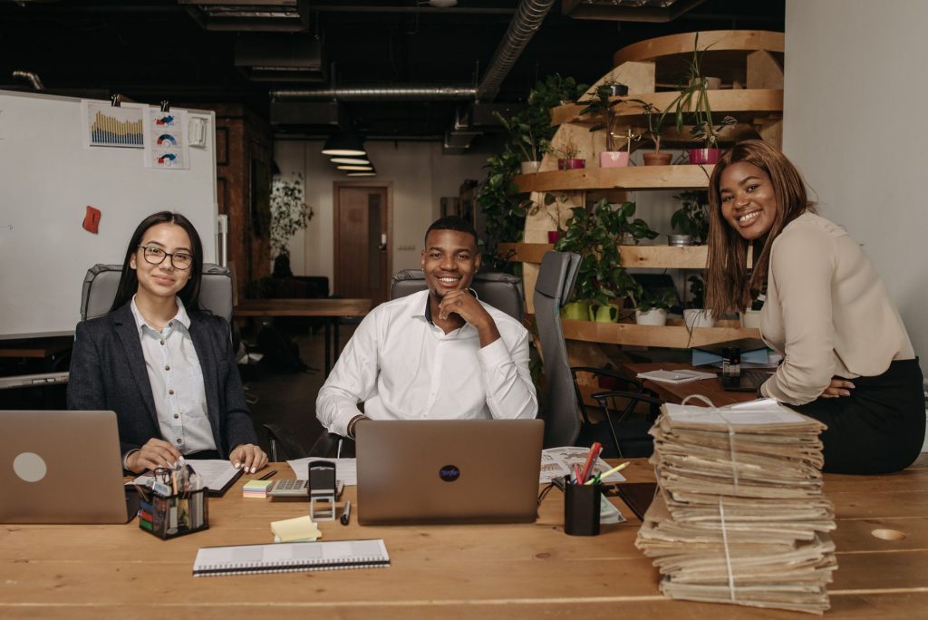 Équipe de collaborateurs souriants travaillant ensemble autour d'une table dans un open space