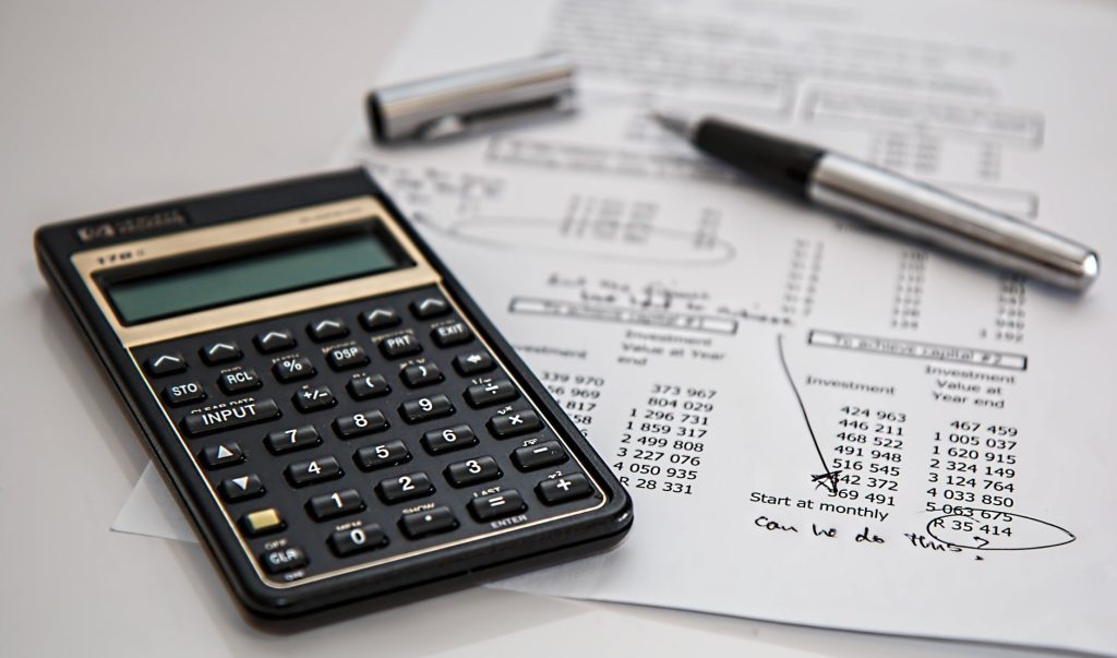 Calculatrice, stylo et documents financiers pour planifier son épargne mensuelle